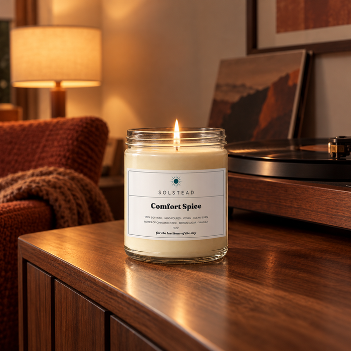Solstead Comfort Spice 9 oz soy candle burning on a wooden sideboard beside a record player