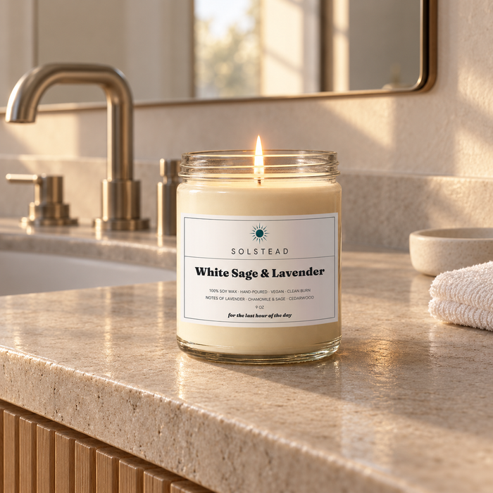 Solstead White Sage & Lavender 9 oz soy candle burning on a stone bathroom vanity beside the sink