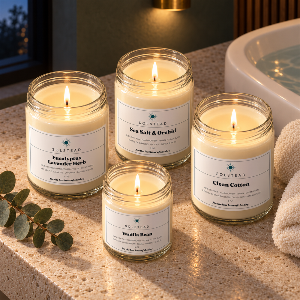 The Unwind Set by Solstead, the four candles glowing on a stone ledge at dusk with eucalyptus stems